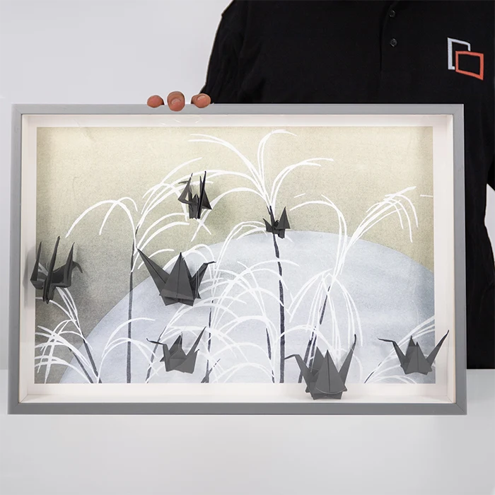Le gru nere realizzate con la tecnica dell’origami spiccano sullo sfondo del poster.